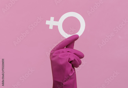 Feminism. Women's power. Hand in rubber cleaning glove holds a female gender symbol venev on a pink background photo