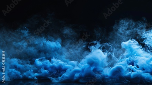 Blue smoke on the floor on a black background. Clouds of fog are located on the ground. Empty wall. Abstract wallpaper for theater and concert design.