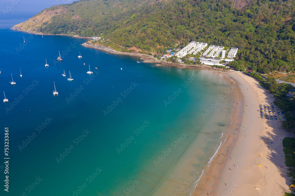 aerial view beautiful blue sky above green sea at Nai Harn beach. .Tourist boats and yachts moored in Nai Harn Bay. .Crowds of tourists relax on the beach. .sea waves crashing on shore background.