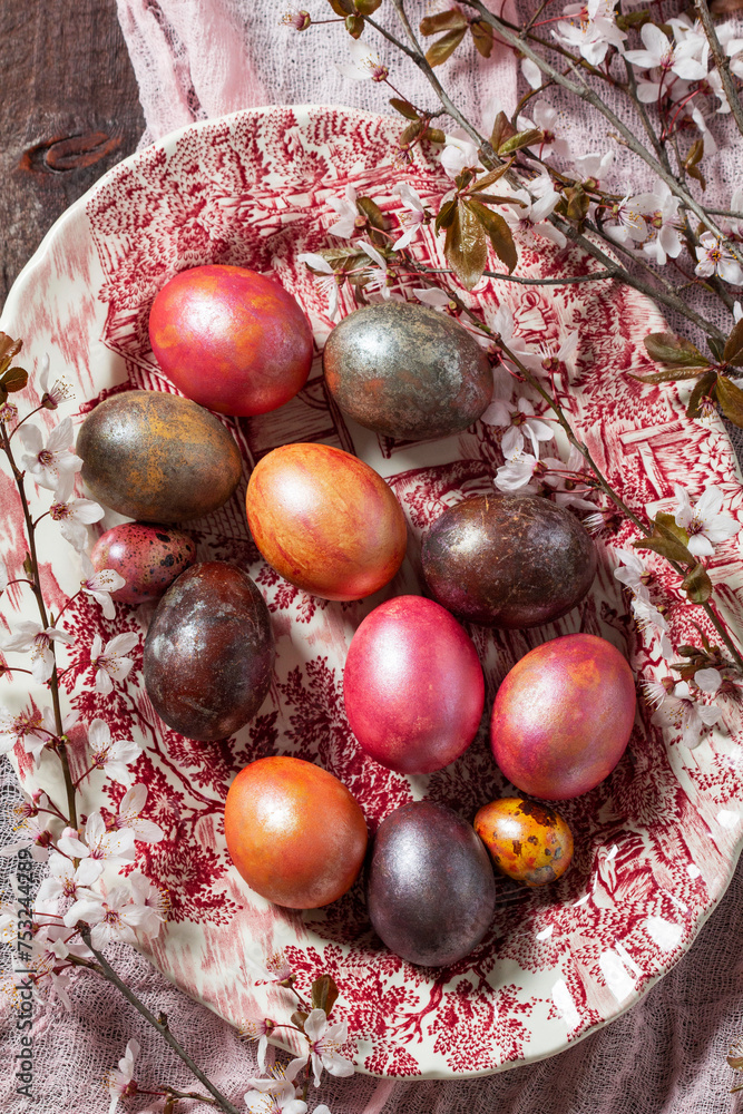 Eggs painted in different colors and covered with mother-of-pearl, and blossoming plum branches. Easter concept.