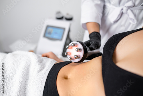 RF body cavitation lifting procedure is employed at the beauty salon to aid a young woman in reducing belly fat.