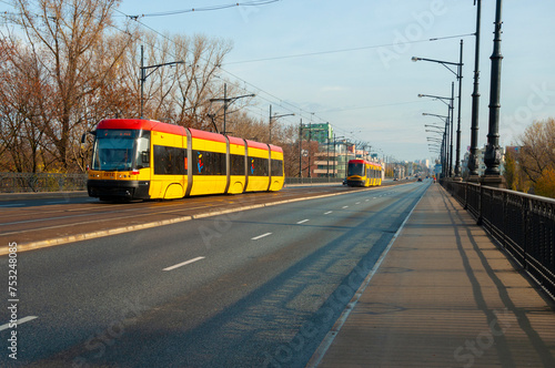 Modern red and yellow tram on city street in Warsaw, Poland. Public transport