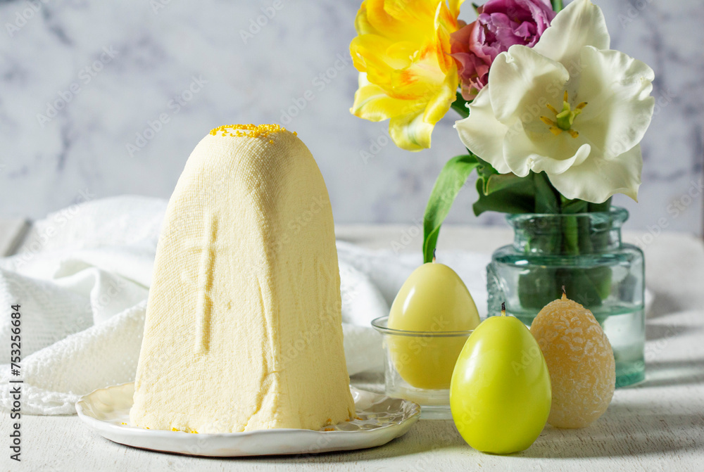 Traditional Slavic Easter dish made from cottage cheese - Paskha, a bouquet of tulips and candles on a light background.