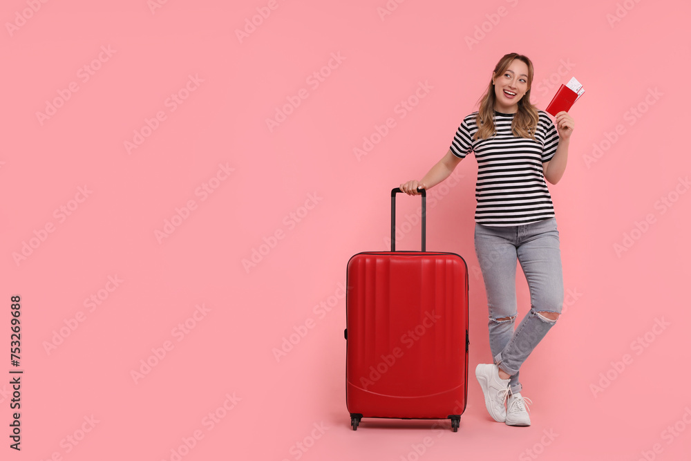 Happy young woman with passport, ticket and suitcase on pink background, space for text Happy young woman with passport, ticket and suitcase on pink background, space for text