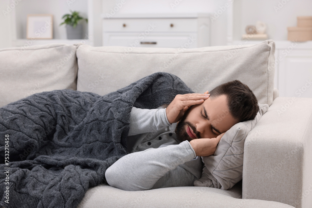 Man suffering from headache on sofa at home Man suffering from headache on sofa at home
