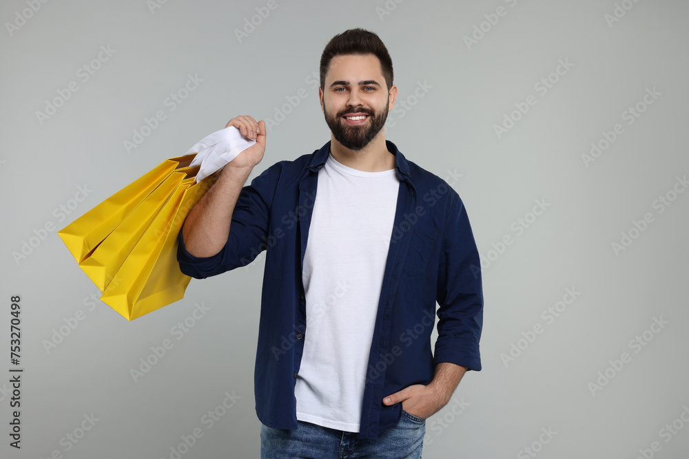 Happy man with many paper shopping bags on grey background Happy man with many paper shopping bags on grey background