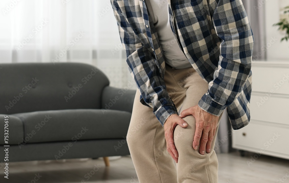 Arthritis symptoms. Man suffering from pain in knee at home