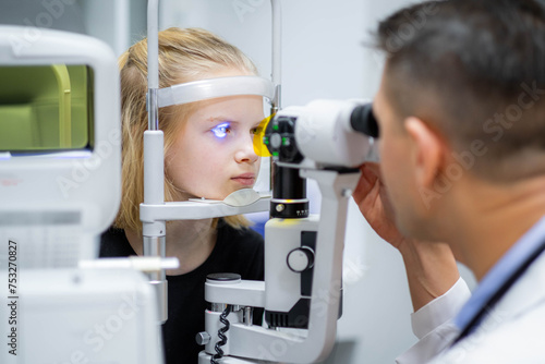 Fototapeta Naklejka Na Ścianę i Meble -  doctor and young patient in eye clinic, girl undergoing an eye test with professional optometrist using advanced diagnostic equipment, pediatric ophthalmology examination