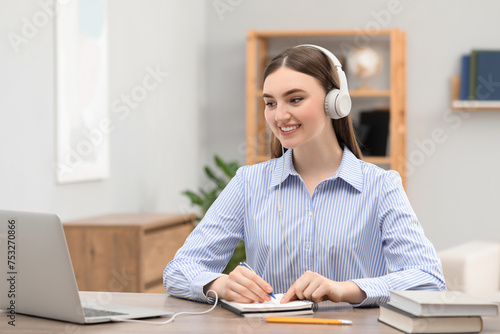 E-learning. woman taking notes during online lesson at table indoors