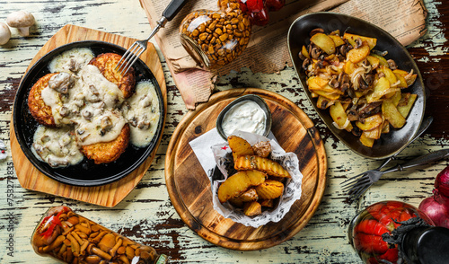 Different dishes from potatoes, fried potato pancakes, homemade potatoes with mushrooms and french fries potatoes in craft paper on wooden background, top view, flat lay