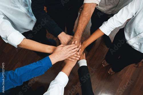 Group of diverse office worker join hand together in office room symbolize business synergy and strong productive teamwork in workplace. Cooperation and unity between business employee. Prudent © Summit Art Creations