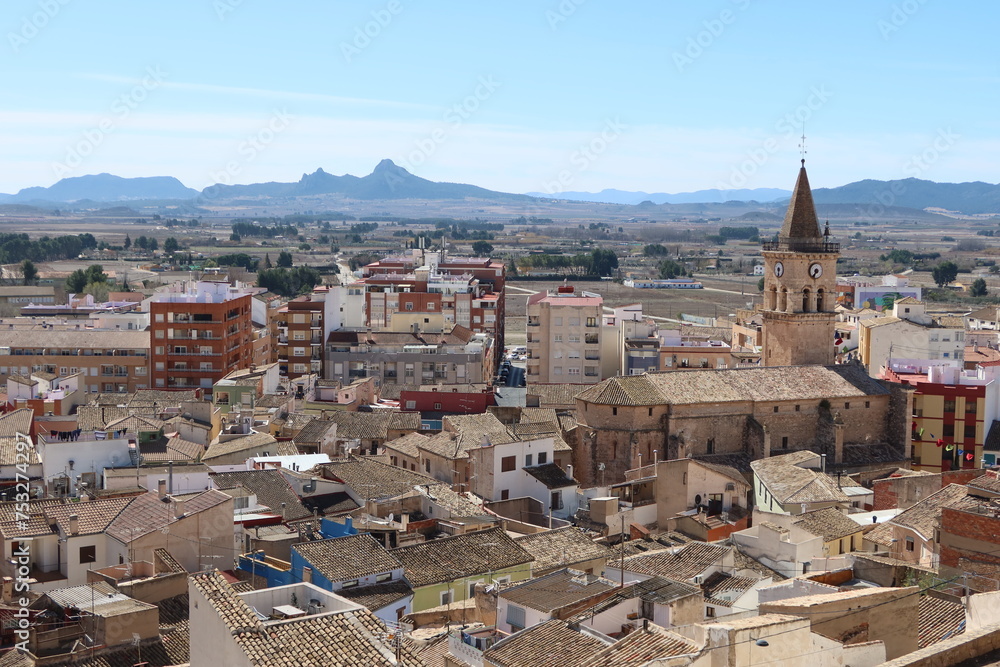 Villena, Alicante, Spain, March 5, 2024: Building and Bell Tower of the Church of Santa Maria in the center of the town with mountains in the background. Villena, Alicante, Spain