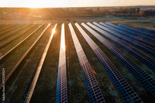 Aerial view of industrial sized solar panel farm during sunset,  illustrating the blend of technology and nature