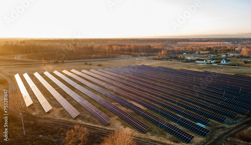 Aerial view of industrial sized solar panel farm during sunset, illustrating the blend of technology and nature