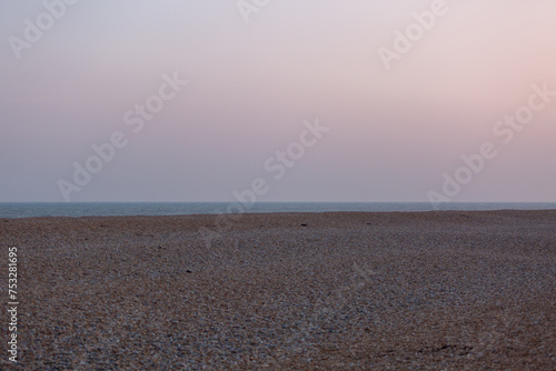 View of the English channel from a shingle beach, Image shows a cloudy evening on the English coast looking out to the North sea with various colours in the sky © J.Woolley