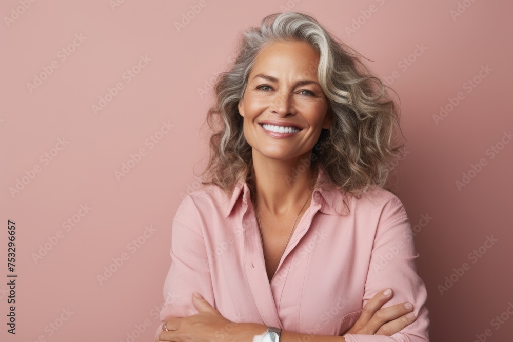 Portrait of smiling senior woman with arms crossed over pink background. Portrait of smiling senior woman with arms crossed over pink background.