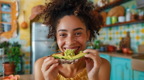 a woman happily eating smashed avocado on toast in a colourful kitchen photo
