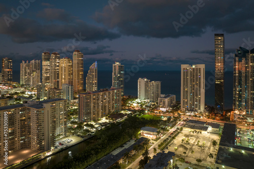 Aerial view of downtown district in Sunny Isles Beach city in Florida  USA. Brightly illuminated high skyscraper buildings in modern american midtown