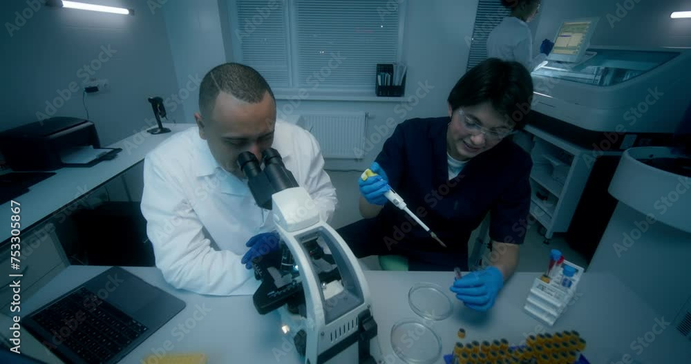 A man and a woman in lab coats are working in a medical laboratory ...