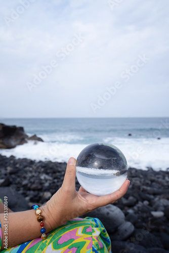 woman meditating on wild beach shore and holding crystal ball