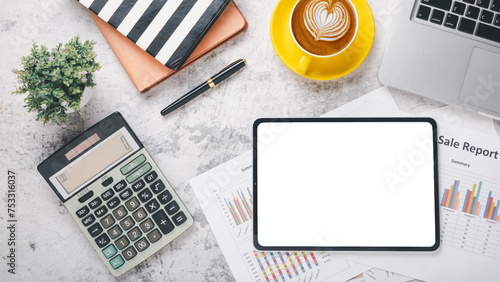 Overhead view of a well-organized desk featuring a digital tablet with a blank screen, financial reports, a calculator, and a cup of coffee, symbolizing strategic business planning and analysis.