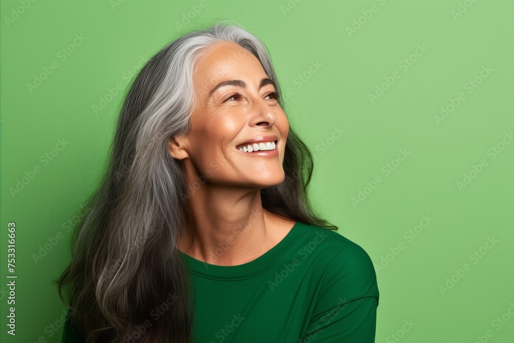 Portrait of smiling senior woman with long grey hair on green background Portrait of smiling senior woman with long grey hair on green background