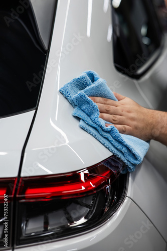 A mechanic wipes the body of a white car with a microfiber cloth.  © Михаил Решетников