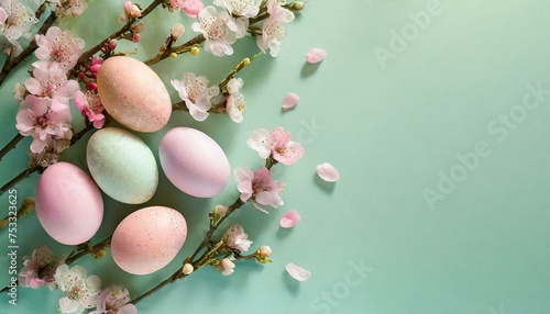 Minimalistic Easter background with eggs in pastel pink colors with spring pink flowers on a light green background with copy space for text.