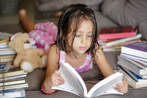 Pausa para Imaginar Criança deitada Entre Contos e Fábulas lendo livros no sofá. photo