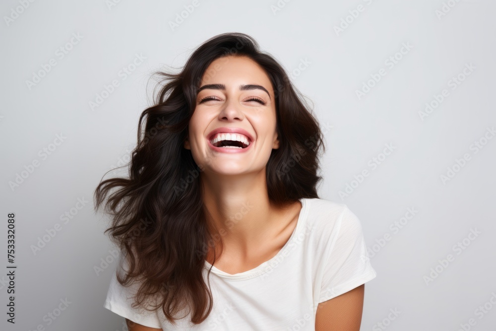 Portrait of a happy young woman laughing with closed eyes against grey background Portrait of a happy young woman laughing with closed eyes against grey background