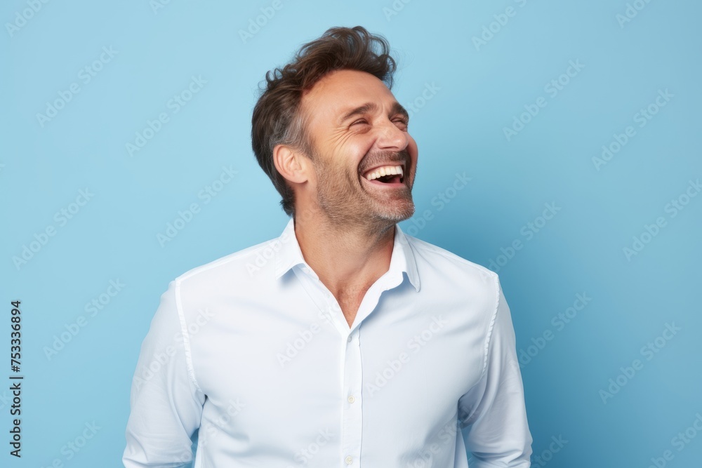 Portrait of a handsome middle age man laughing and looking away against blue background Portrait of a handsome middle age man laughing and looking away against blue background