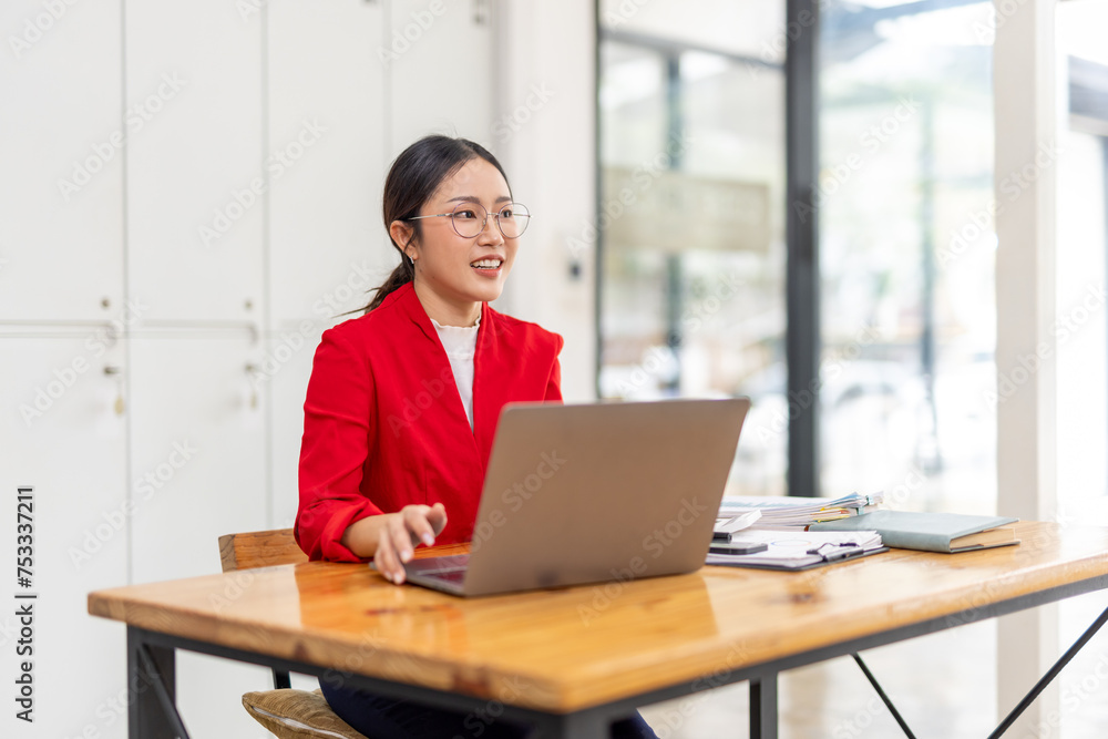 Portrait of Happy young business asian woman in red suit sitting at her desk in the office business finance concept. Portrait of Happy young business asian woman in red suit sitting at her desk in the office business finance concept.