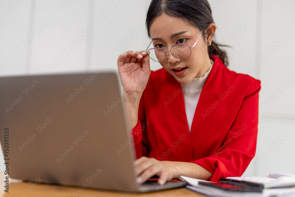 Portrait of Happy young business asian woman in red suit sitting at her desk in the office business finance concept. Portrait of Happy young business asian woman in red suit sitting at her desk in the office business finance concept.