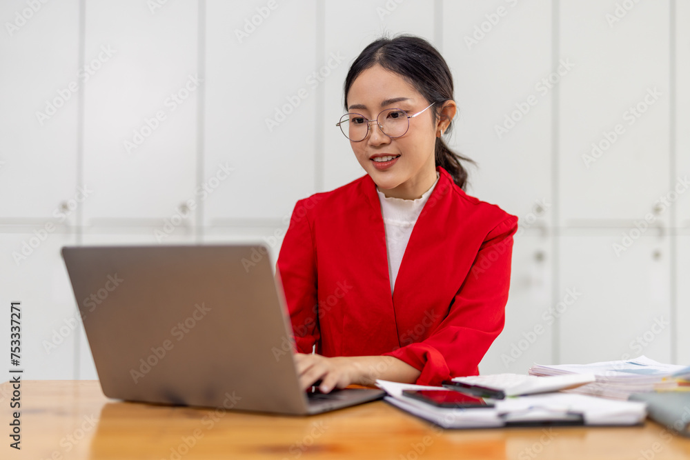 Portrait of Happy young business asian woman in red suit sitting at her desk in the office business finance concept. Portrait of Happy young business asian woman in red suit sitting at her desk in the office business finance concept.