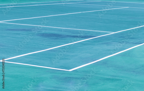 The white lines of an empty outdoor tennis court viewed from an angle. Point of view.