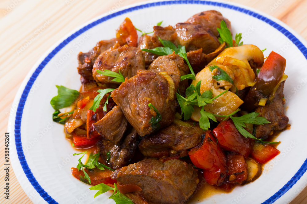 Delicious meat stew with bell pepper, tomatoes and mushrooms (Kavarma) served fresh greens. Bulgarian cuisine