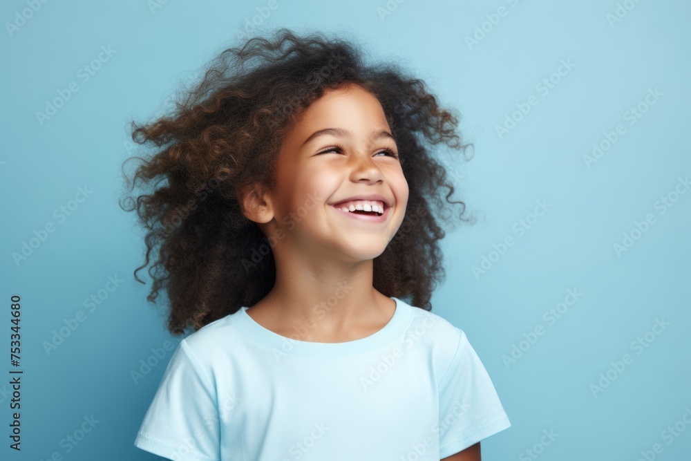 Happy african american little girl with curly hair on blue background Happy african american little girl with curly hair on blue background