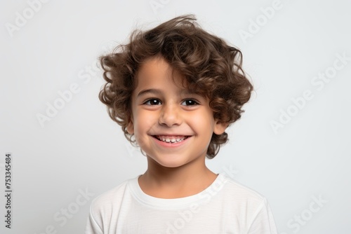 Portrait of a cute little boy with curly hair on a gray background