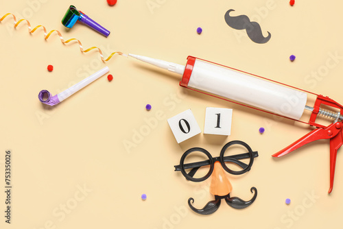 Funny glasses with construction adhesive and party decor on beige background. April Fools Day