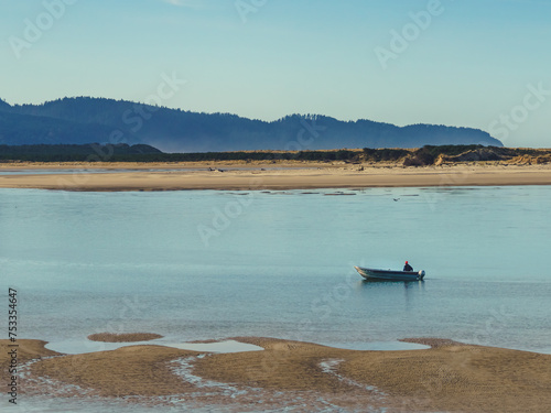 small boat navigates an empty Pacific coast bay on a chilly morning photo