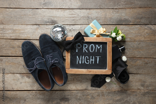 Chalkboard with text PROM NIGHT, male shoes and gift box on wooden background photo