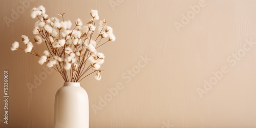 Minimal floral decor indoors with dried white flowers on beige wall, showcasing a cozy home atmosphere. photo