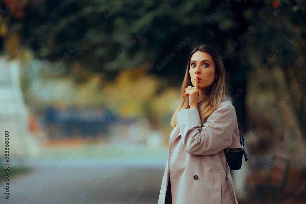Woman Making Sush Gesture with Finger on the Lips. Mysterious girl making hush-hush sign walking in the park 
