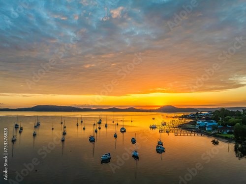 Aerial sunrise over the water with boats and clouds