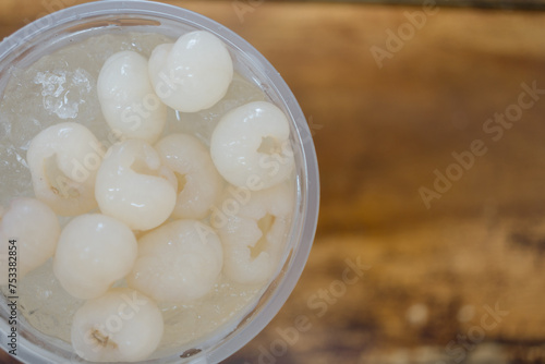 Longan juice in a clear plastic glass with wood brown background