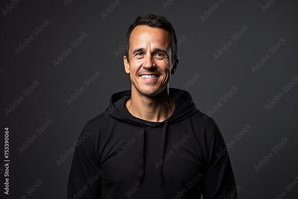 Portrait of a smiling man in black hoodie over dark background
