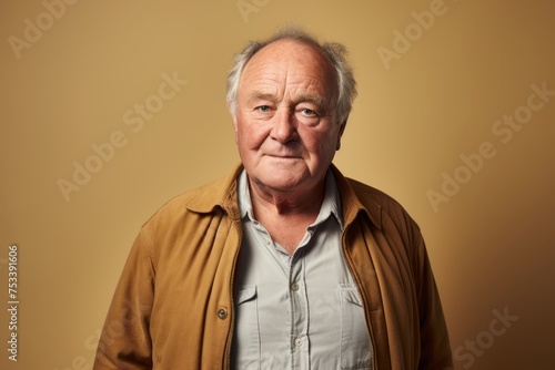 Portrait of an elderly man on a yellow background. Studio shot.