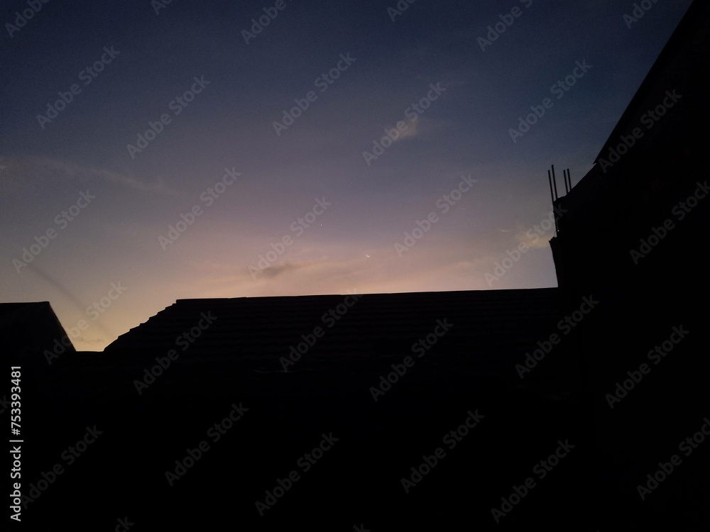 housing silhouette at sunrise with dazzling light colors, wide shot from a lower angle, beautiful Indonesian sunrise