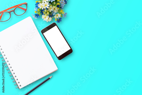 Office desk with notebooks,smartphone,red glasses,pencil,fresh flower ont blue table background. Top view with copyspace for desigh. Business and finance concept