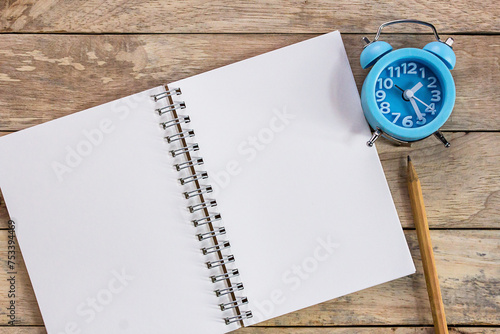 Top view with blank empty notebooks or notepad, alarm clock and pencil on wood table.